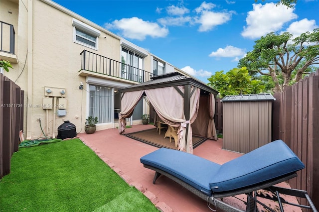 back of property with a gazebo, a balcony, a shed, and a patio