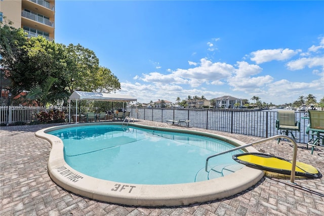 view of swimming pool featuring a water view and a patio area