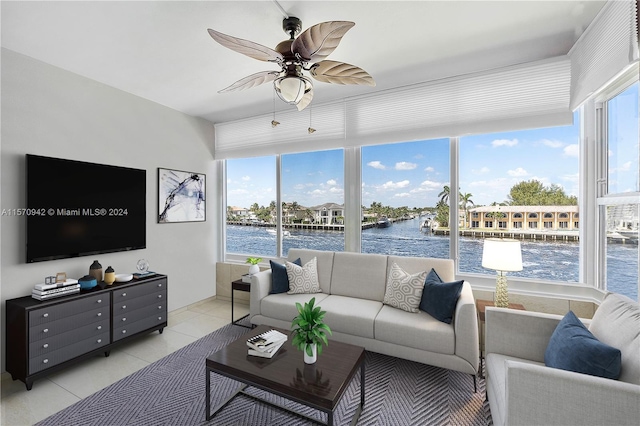 living room with light tile patterned floors, a water view, plenty of natural light, and ceiling fan