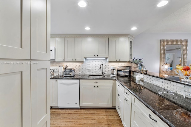 kitchen with dark stone countertops, sink, light hardwood / wood-style floors, and white appliances