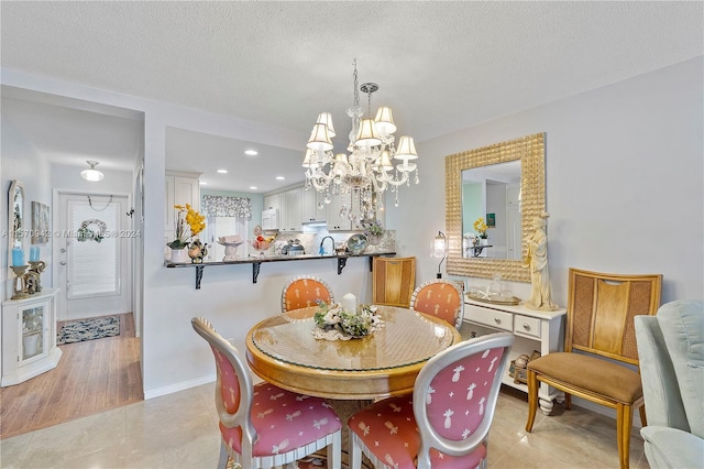 dining room with a chandelier, a textured ceiling, and light wood-type flooring