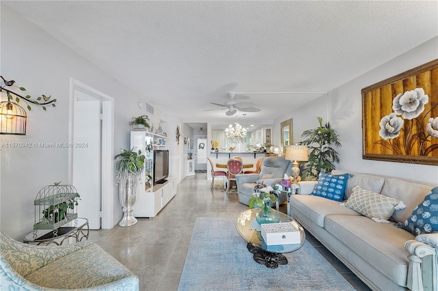 living room with ceiling fan with notable chandelier and a textured ceiling