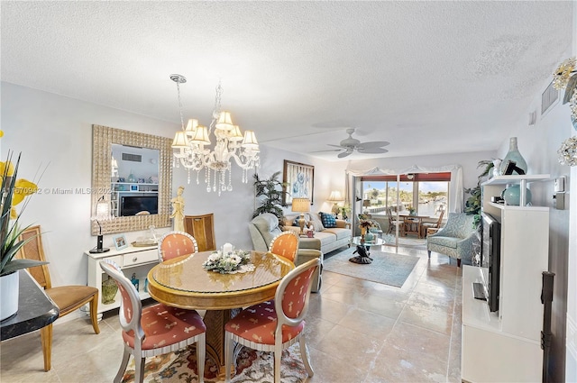 tiled dining space featuring ceiling fan with notable chandelier and a textured ceiling