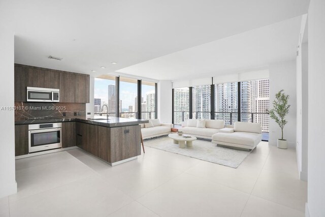 living room featuring sink, a wall of windows, and light tile patterned floors