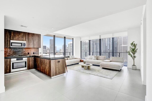 kitchen with stainless steel appliances, kitchen peninsula, expansive windows, decorative backsplash, and sink