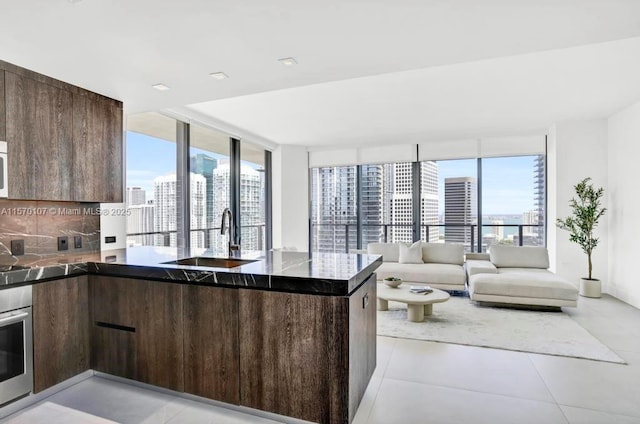 kitchen with a sink, dark brown cabinetry, modern cabinets, and a city view