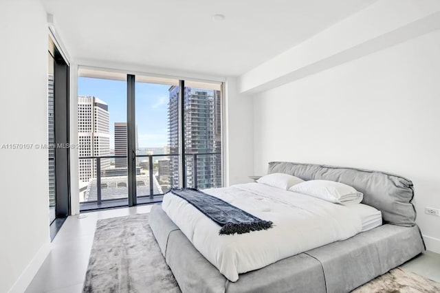 bedroom with access to outside, a view of city, baseboards, and a wall of windows