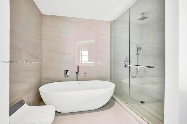 bathroom featuring a soaking tub, a tile shower, tile walls, and toilet