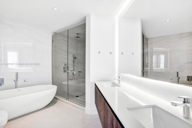 bathroom featuring double vanity, a stall shower, a sink, and a soaking tub