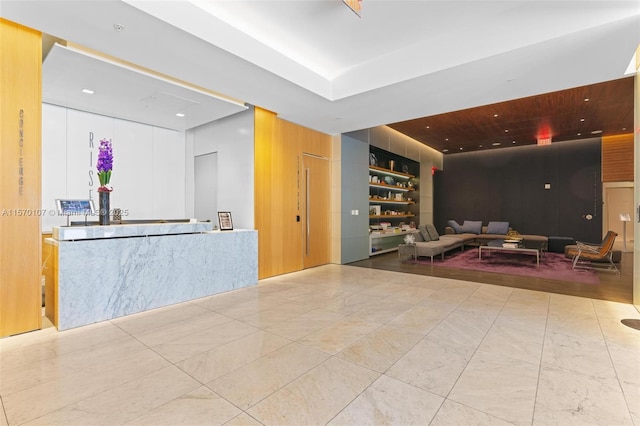 interior space with wooden walls, built in shelves, and marble finish floor