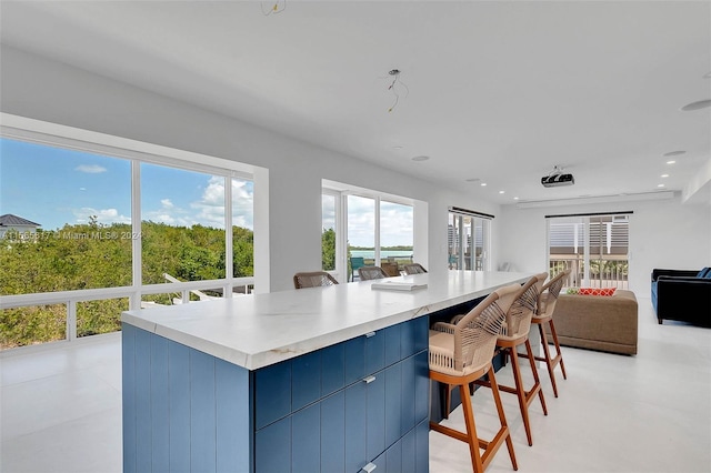 kitchen featuring a center island, light tile floors, blue cabinets, and a kitchen bar