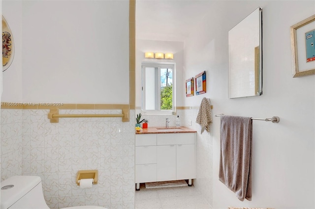 bathroom featuring vanity with extensive cabinet space, toilet, tile flooring, and tile walls