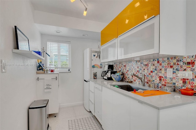 kitchen featuring white cabinets, light tile flooring, backsplash, sink, and track lighting