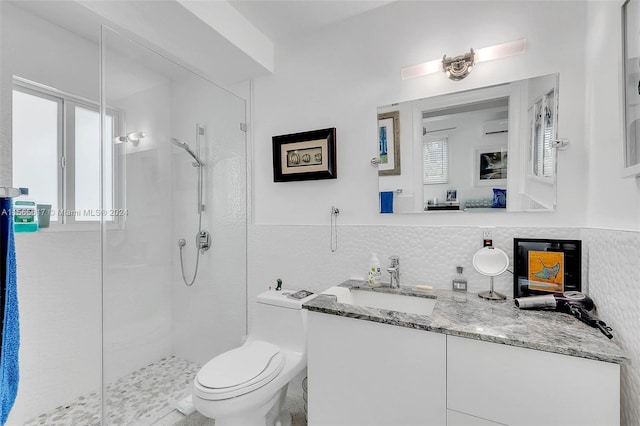 bathroom with oversized vanity, tasteful backsplash, toilet, a tile shower, and a wealth of natural light