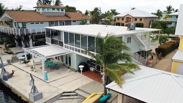 rear view of house featuring a patio, a balcony, and a sunroom