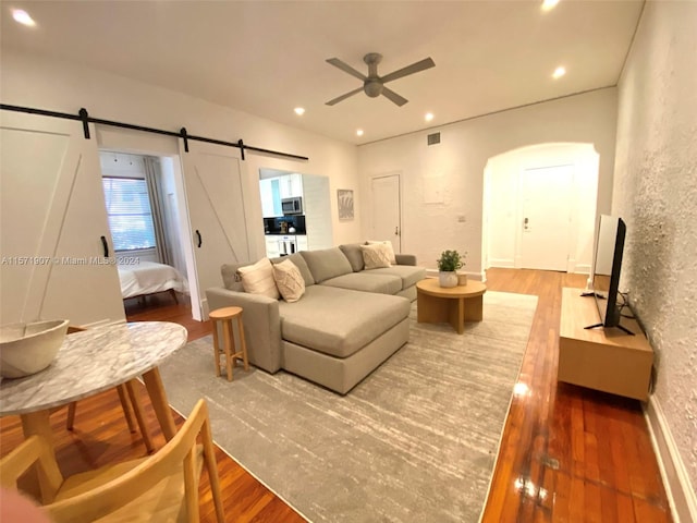 living room featuring ceiling fan, hardwood / wood-style flooring, and a barn door