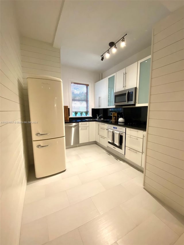 kitchen with light tile floors, appliances with stainless steel finishes, white cabinets, and track lighting