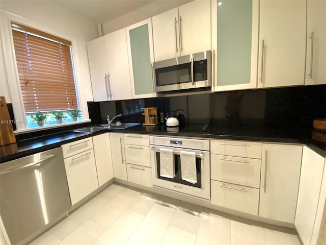 kitchen featuring tasteful backsplash, appliances with stainless steel finishes, white cabinetry, and sink