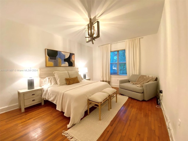 bedroom featuring an inviting chandelier and dark hardwood / wood-style flooring