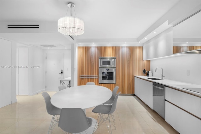 kitchen with stainless steel appliances, white cabinets, sink, a notable chandelier, and light tile floors