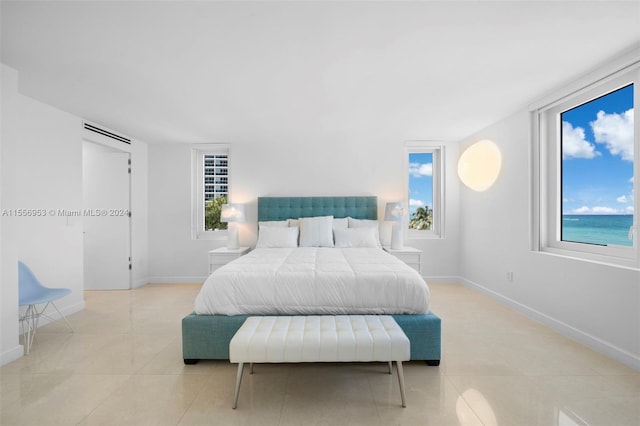 tiled bedroom featuring multiple windows and a water view