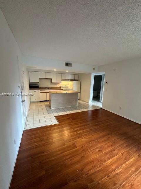 3985 W Mcnab Rd Unit A111, Pompano Beach, FL 33069 - unfurnished living room featuring light wood-style flooring, a textured ceiling, and baseboards