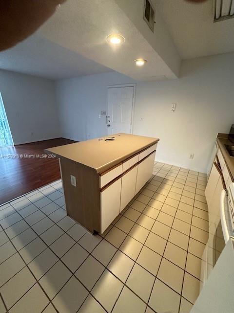 3985 W Mcnab Rd Unit A111, Pompano Beach, FL 33069 - kitchen featuring light tile patterned floors, white cabinetry, recessed lighting, a center island, and light countertops