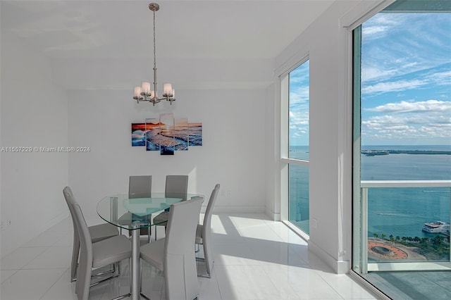 dining area with a water view, light tile floors, and a chandelier