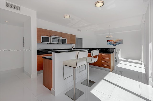 kitchen featuring a center island, decorative light fixtures, light tile flooring, a notable chandelier, and a kitchen bar