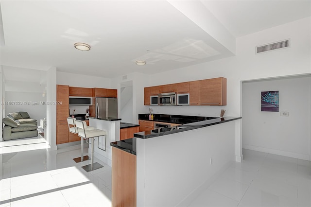 kitchen with a kitchen breakfast bar, stainless steel appliances, a center island, and light tile flooring