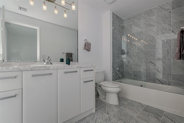 full bathroom with tiled shower / bath combo, tile floors, vanity, and toilet