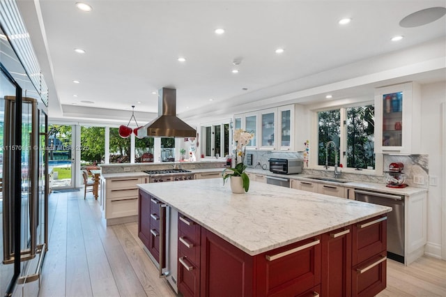 kitchen featuring appliances with stainless steel finishes, island range hood, a kitchen island, and sink