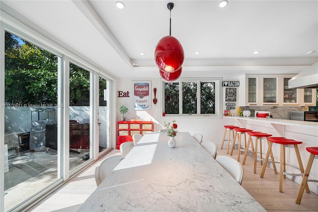 dining space featuring light hardwood / wood-style floors and a raised ceiling