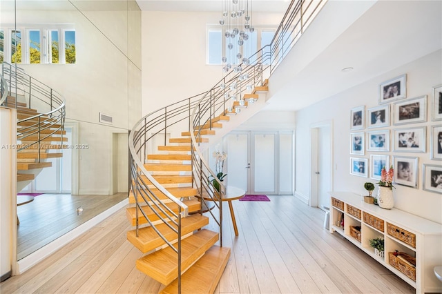 stairs featuring hardwood / wood-style floors, a chandelier, a high ceiling, and french doors