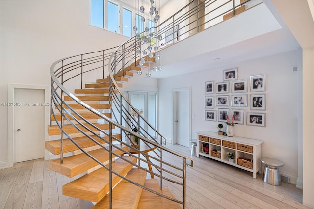 stairs with a chandelier, a towering ceiling, and hardwood / wood-style flooring