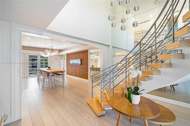 stairs featuring hardwood / wood-style floors, an inviting chandelier, and a raised ceiling