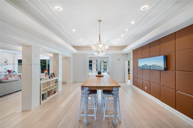 dining area featuring a notable chandelier, light hardwood / wood-style floors, and a raised ceiling