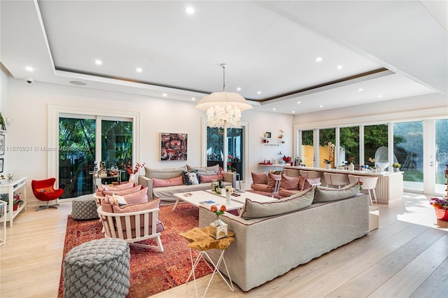 living room with a chandelier, french doors, light hardwood / wood-style floors, and a tray ceiling