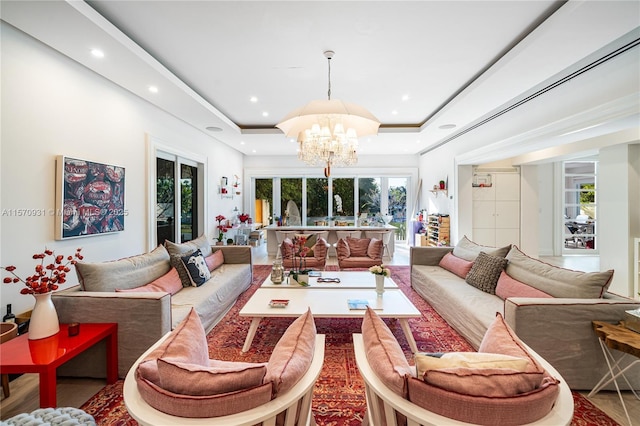 living room with an inviting chandelier and a raised ceiling