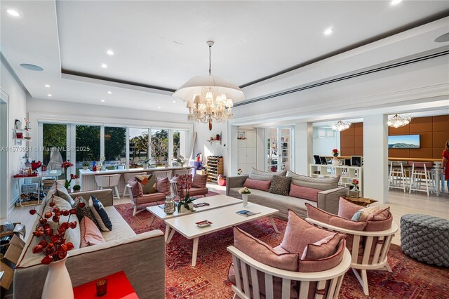 living room with a chandelier, hardwood / wood-style floors, and a raised ceiling