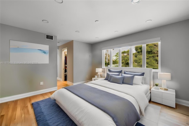 bedroom with light wood-type flooring, a walk in closet, and a closet