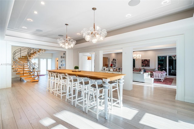 kitchen featuring a tray ceiling, light hardwood / wood-style flooring, decorative light fixtures, and wood counters