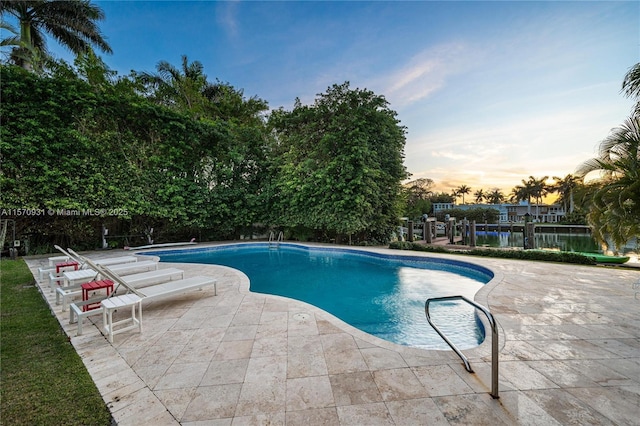 pool at dusk featuring a patio area