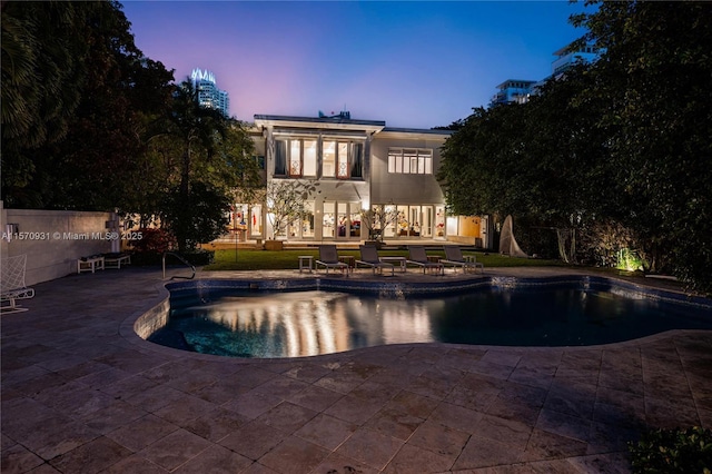 pool at dusk with a patio area