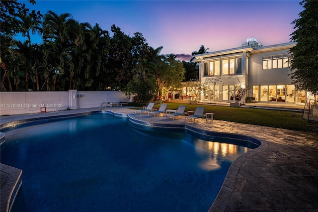 pool at dusk with a patio area