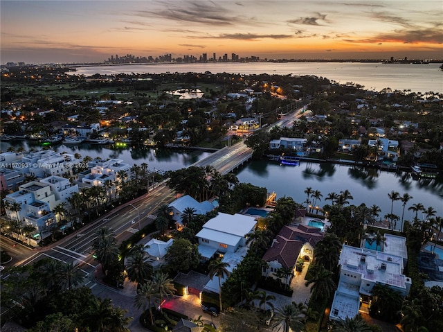 aerial view at dusk featuring a water view