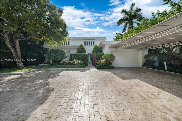 6320 Allison Rd, Miami Beach, FL 33141 - view of front of house featuring decorative driveway, a garage, and stucco siding