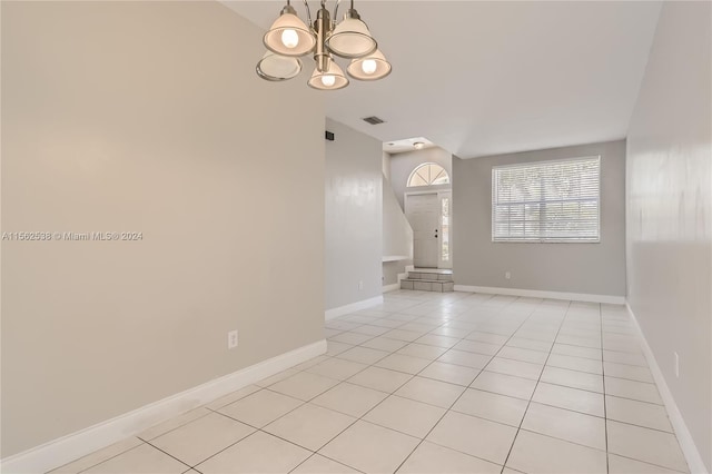 empty room with an inviting chandelier and light tile floors