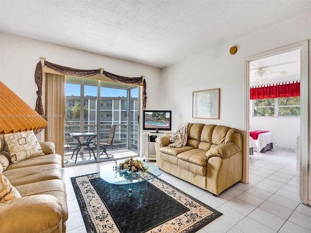 living room featuring ceiling fan, light tile flooring, and a textured ceiling