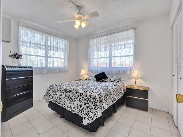 bedroom with a closet, a textured ceiling, ceiling fan, and light tile flooring